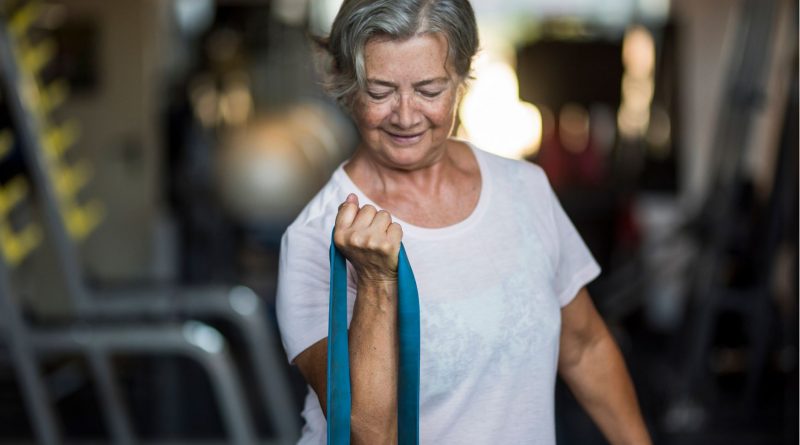 Starsza kobieta wykonuje ćwiczenia fizyczne na siłowni.